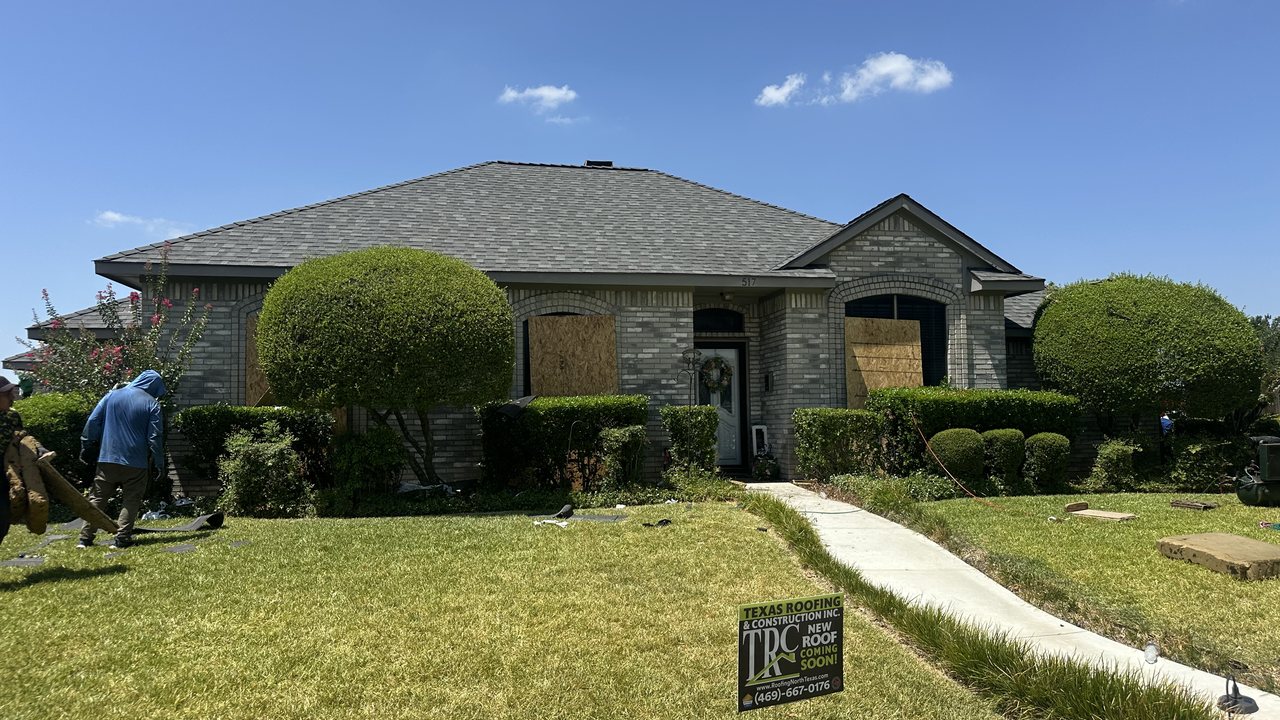 Storm-damaged home with boarded windows before Texas Roofing & Construction restoration